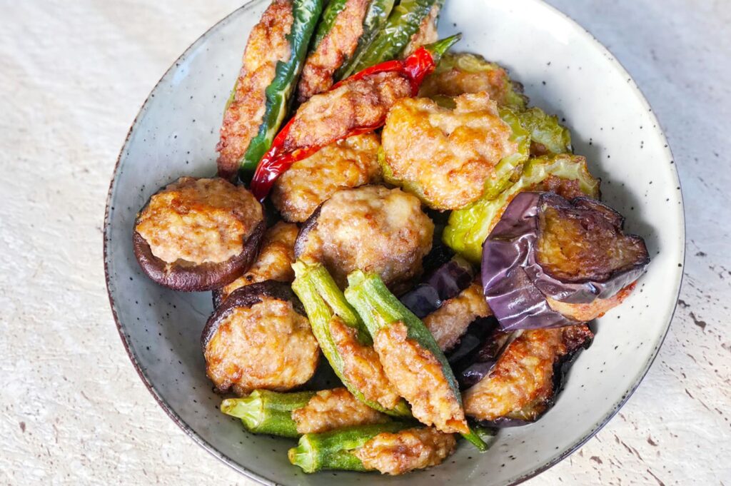 A bowl of yong tau foo featuring fried eggplant and assorted vegetables, showcasing a colorful and appetizing dish.