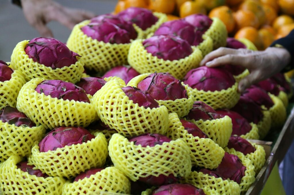A woman holds a basket filled with vibrant red and yellow fruits, showcasing a colorful assortment of fresh produce.
