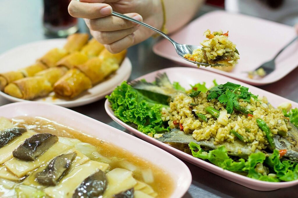 A person enjoying a bowl of healthy hawker food, using a fork to eat.