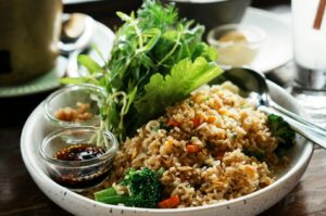 A bowl of brown rice mixed with broccoli and carrots, accompanied by a spoon, highlighting high-fiber foods.