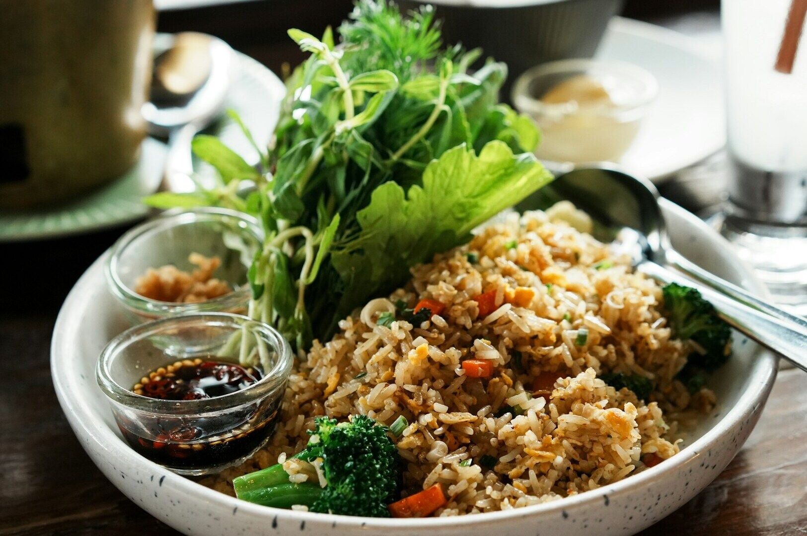 A bowl of brown rice mixed with broccoli and carrots, accompanied by a spoon, highlighting high-fiber foods.