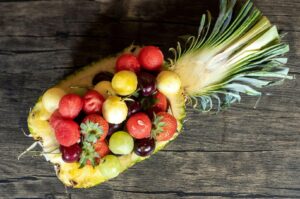 A pineapple topped with assorted fruits, highlighting its dietary fiber content and vibrant colors.