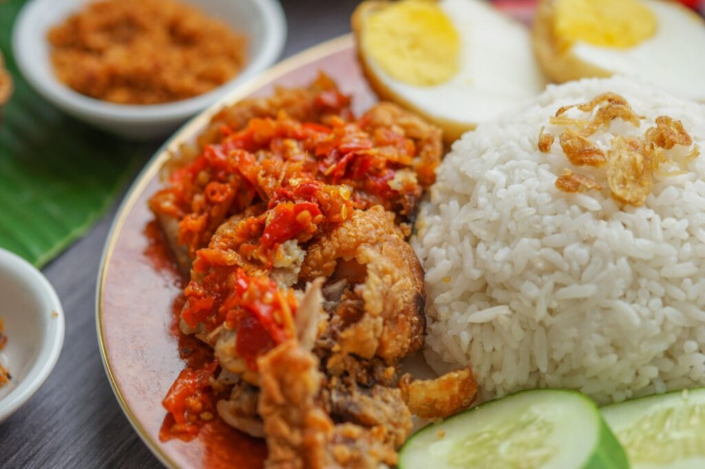 Chicken Rice dish with crispy fried chicken, fluffy rice, and a sunny-side-up egg on the side.