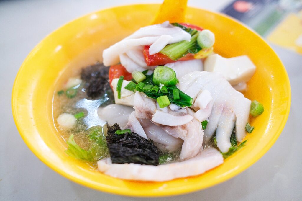 A bowl of sliced fish soup filled with colorful vegetables and tender pieces of meat.