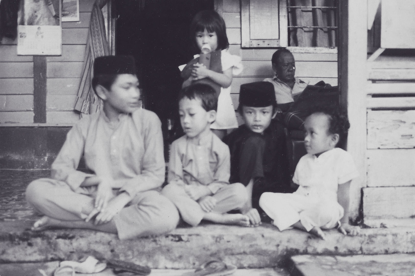Faded Photo of Children sitting cross-legged on a porch
