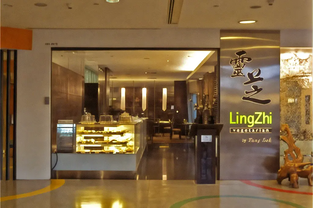 Modern restaurant interior with a sign reading "greendot" in soft yellow lighting. Wooden furnishings and digital menu boards create a warm, welcoming atmosphere.
