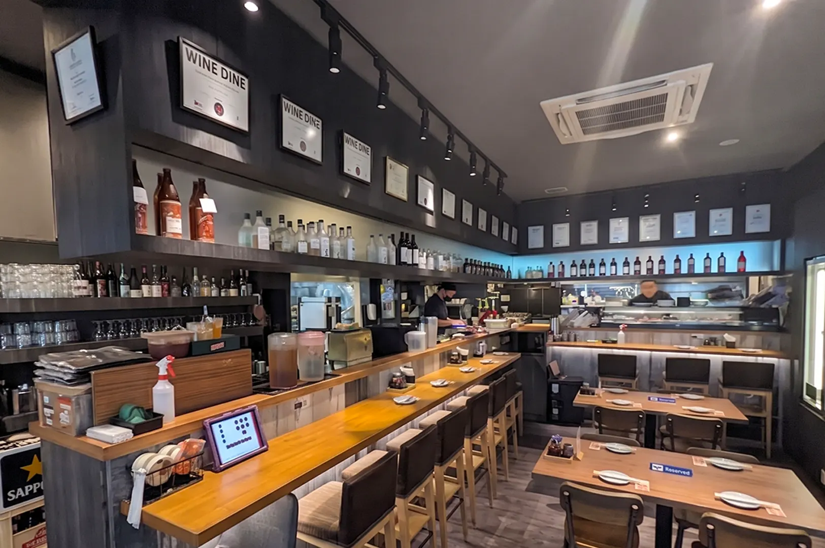 Modern Japanese izakaya restaurant interior in Singapore with wooden counter bar seating and dining tables.