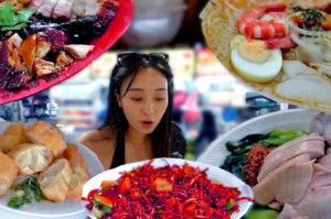 A woman looks surprised, surrounded by plates of vibrant food: roasted meats, noodle soup, sliced rolls, red salad, and poached chicken. The tone is lively.