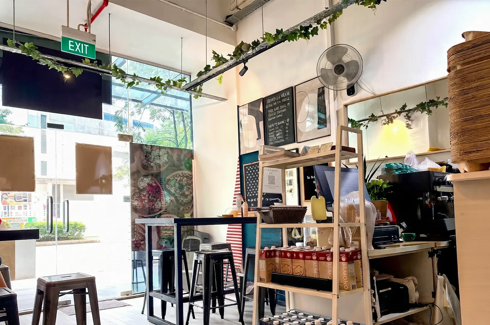 Interior view of The Good Boys cafe, featuring high-top bar seating, a menu board, and beverage display shelves.