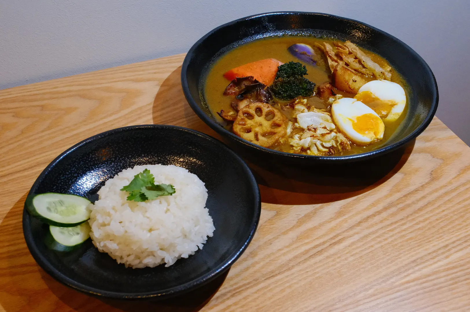 Soup Curry by Ki-setsu featuring Hokkaido soup curry with fried vegetables, boiled egg, and a side bowl of rice.