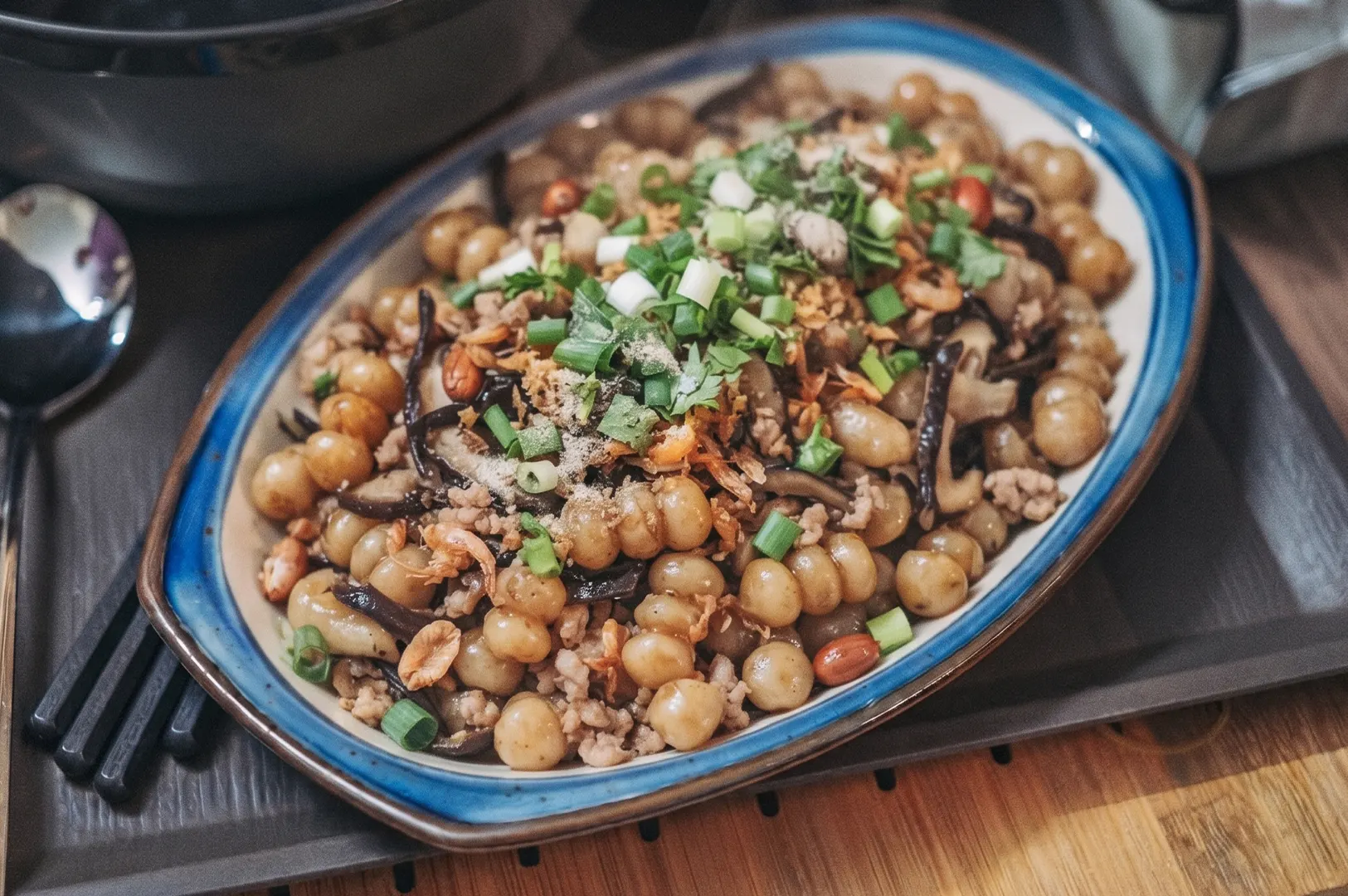 A plate of Hakka Abacus Seeds, a traditional stir-fried taro and yam dumpling dish topped with minced pork, wood ear mushrooms, dried shrimp, and scallions.