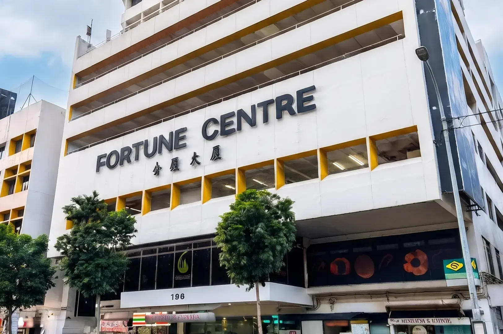 Exterior facade of Fortune Centre building with white walls, yellow accents, and trees in Singapore.