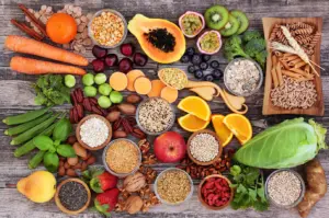 Assorted healthy foods on a wooden table, including fruits, vegetables, grains, and spices. The colorful arrangement conveys freshness and variety.-Whole-food