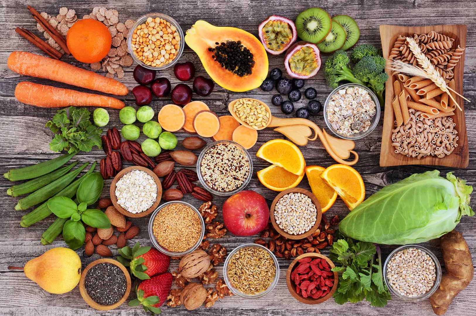 Assorted healthy foods on a wooden table, including fruits, vegetables, grains, and spices. The colorful arrangement conveys freshness and variety.-Whole-food