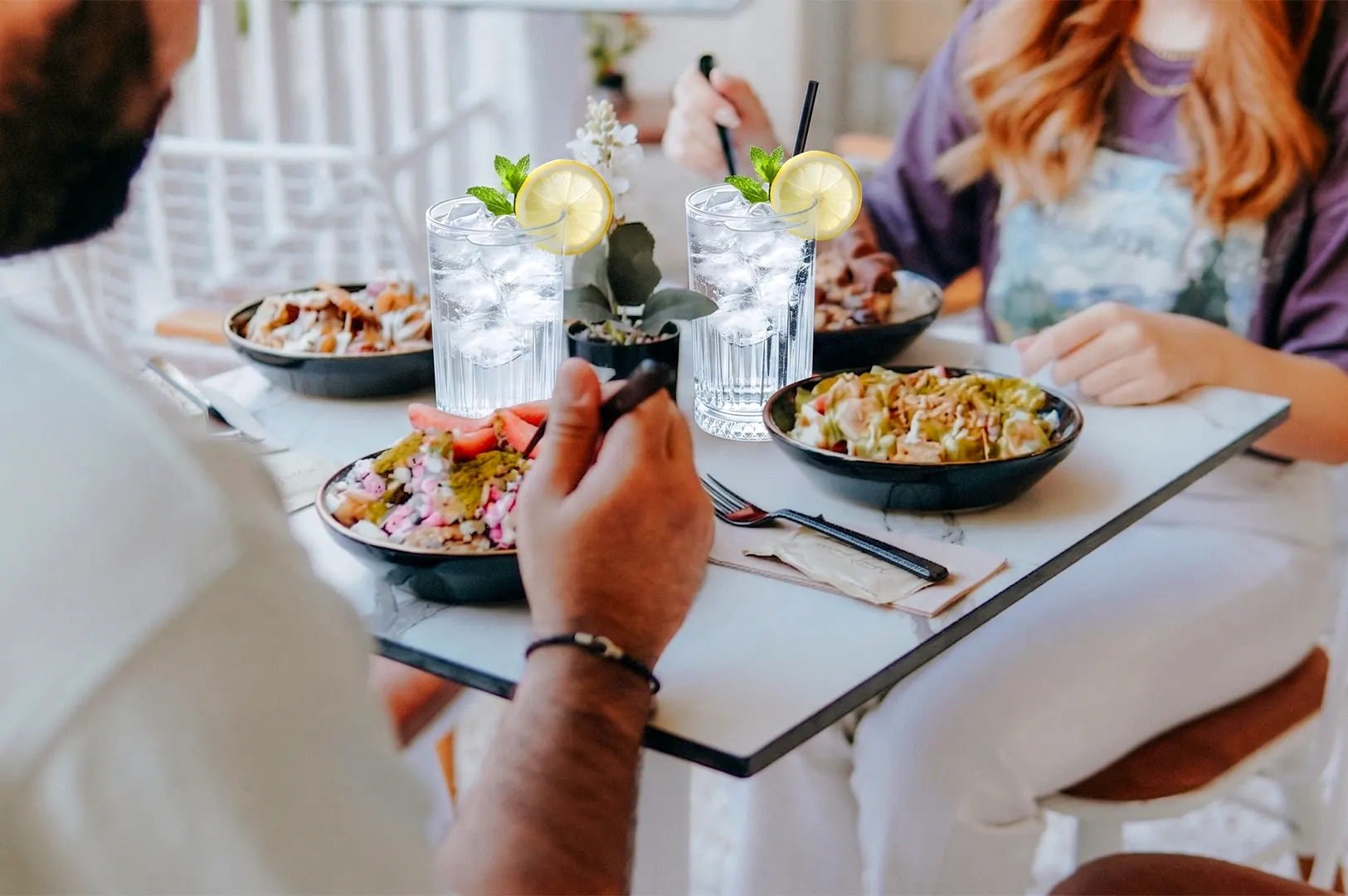 Friends enjoying a healthy meal of colorful grain bowls and refreshing drinks.