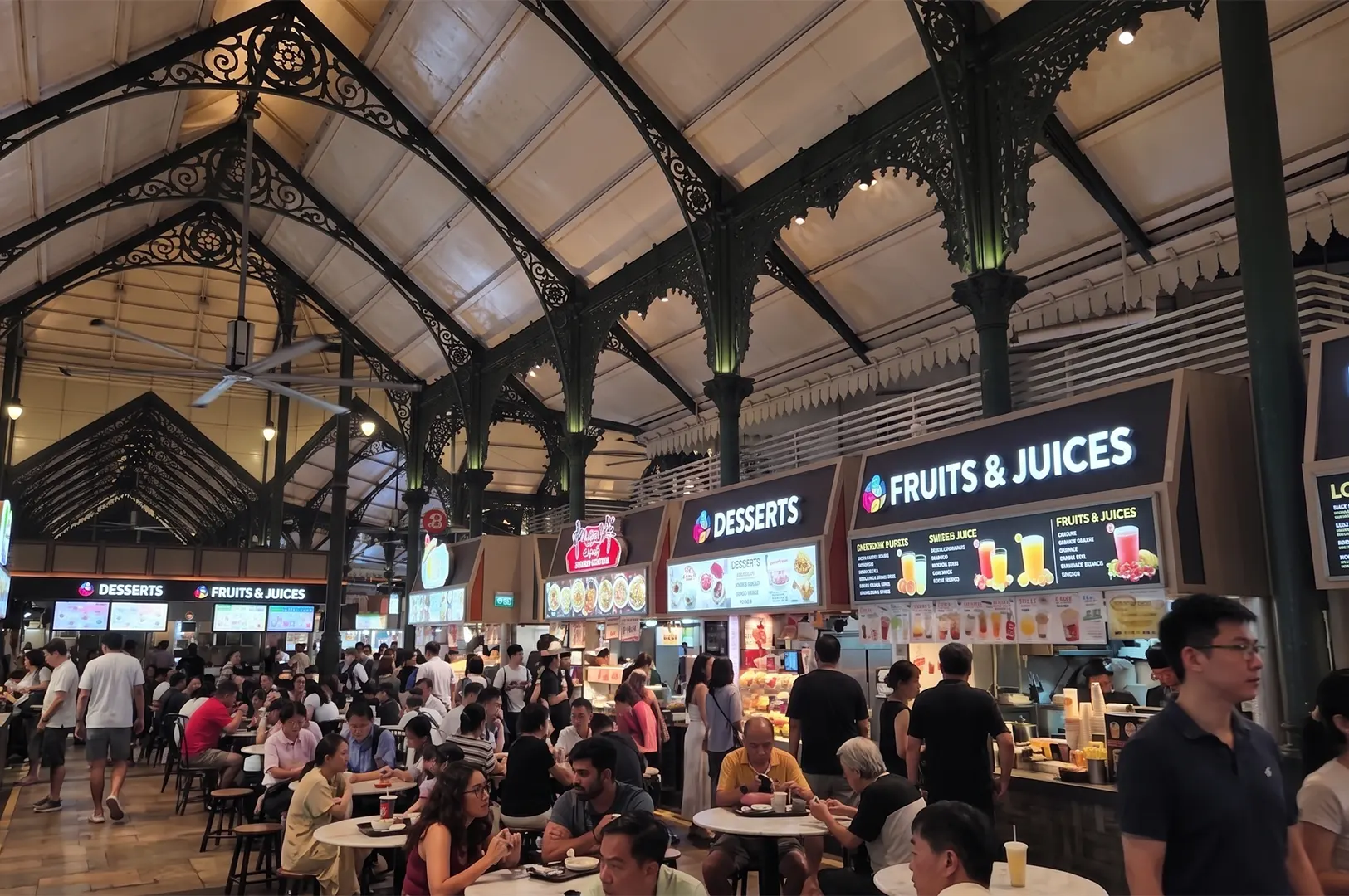 Crowded indoor food court at Lau Pa Sat market in Singapore with Victorian-style iron architecture and various dessert and juice stalls.