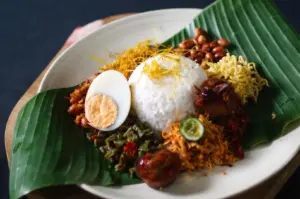 Nasi campur with rice, hard-boiled egg, and side dishes served on a banana leaf.