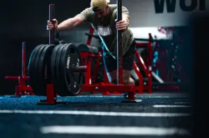 Man pushing a heavy weighted sled in a gym during strength training workout.