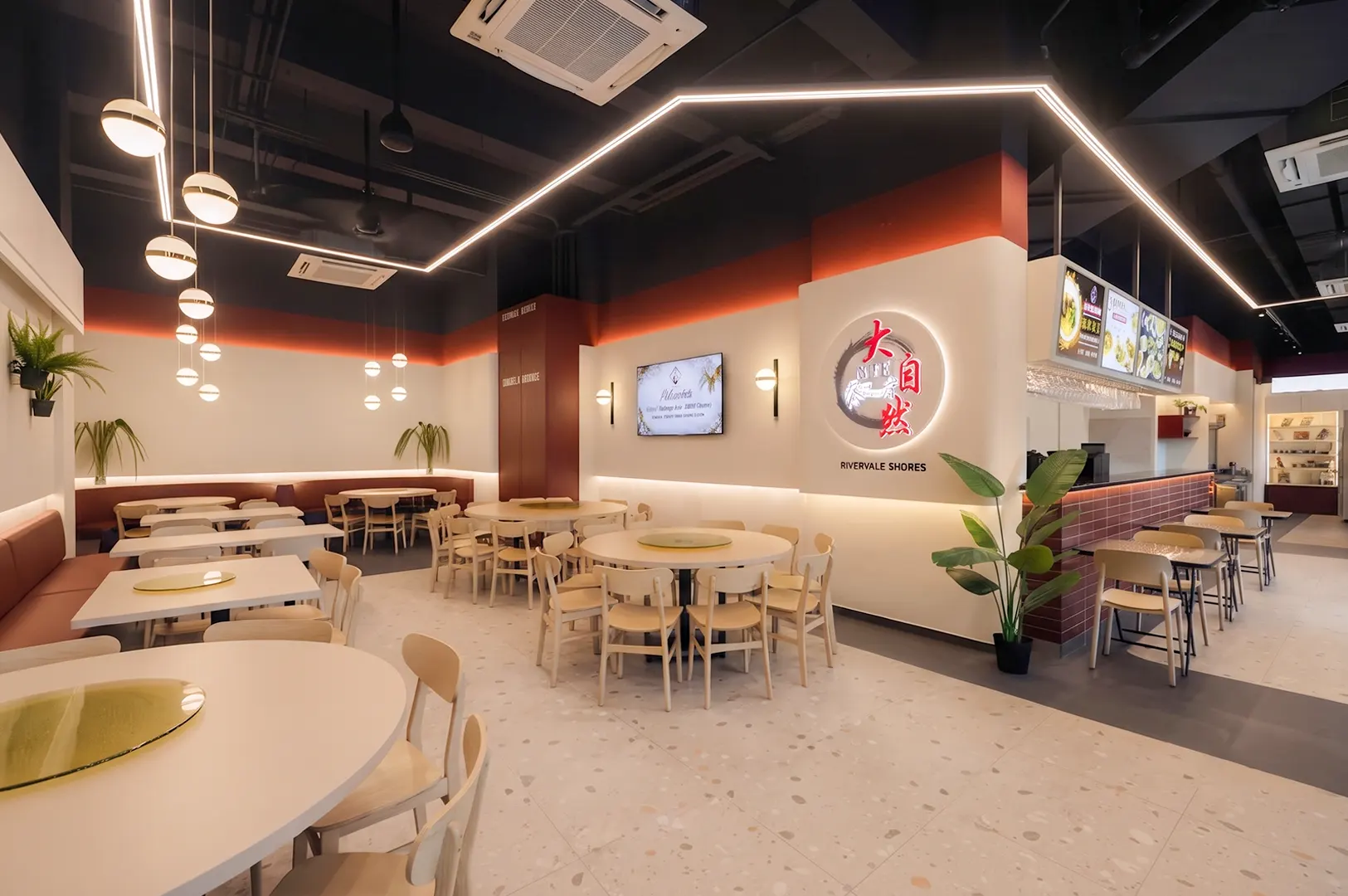Spacious and modern interior dining area at Nature Vegetarian Delights in Sengkang featuring round tables, warm lighting, and a clean ambiance.