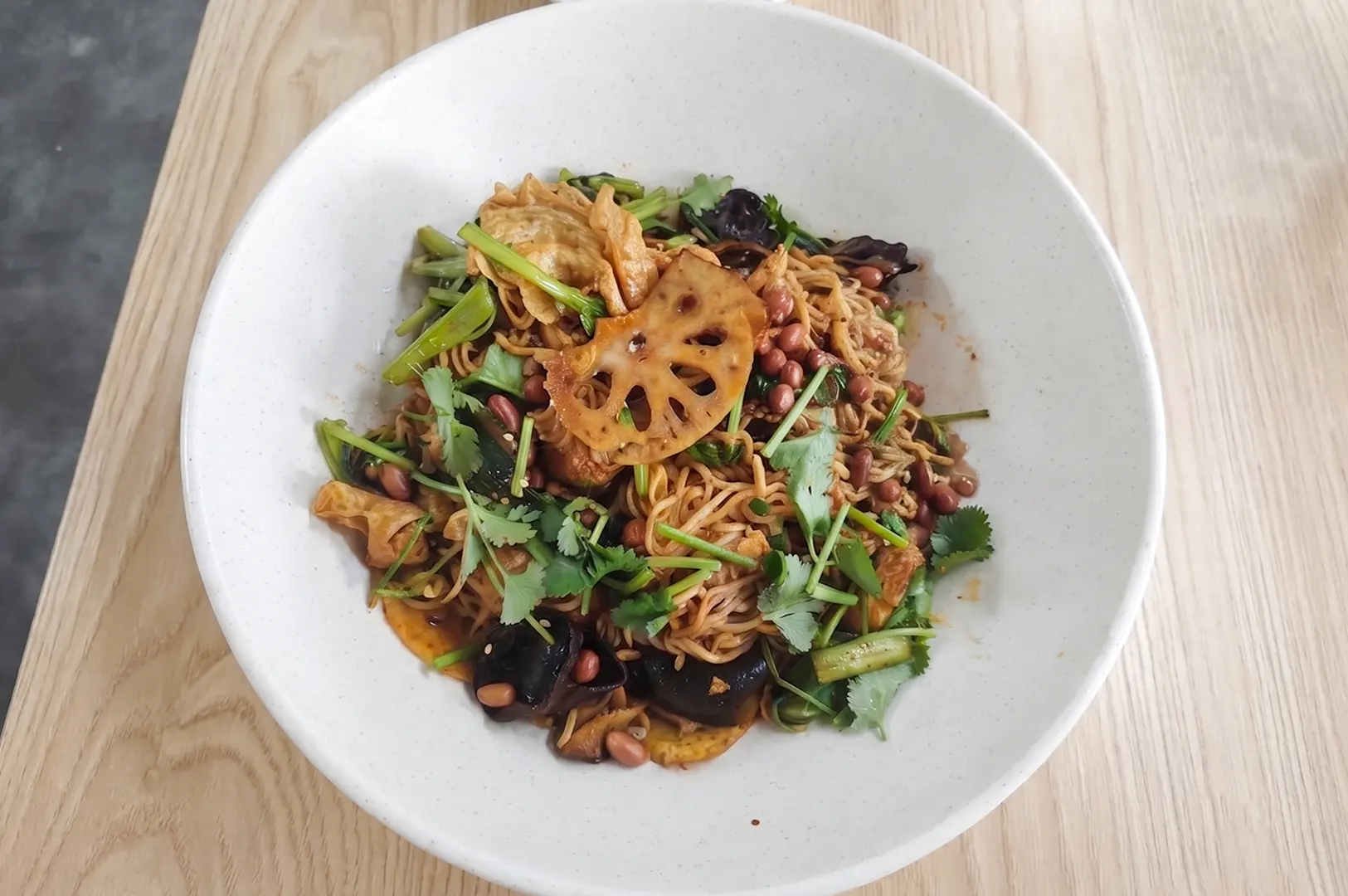 A bowl of vegetarian mala xiang guo stir-fry with lotus root, peanuts, and noodles.