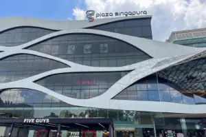 Exterior facade of Plaza Singapura shopping mall in Singapore under a cloudy blue sky.