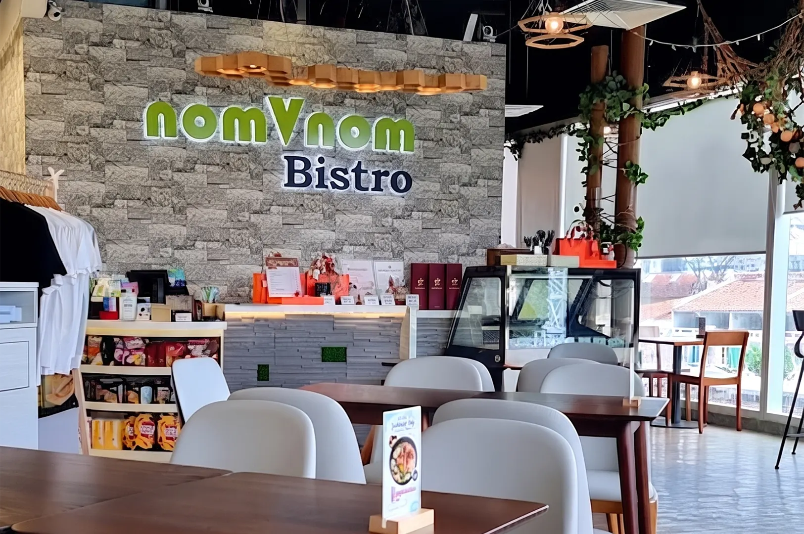 Interior of nomVnom Bistro plant-based restaurant featuring modern seating, a stone accent wall, and the logo.