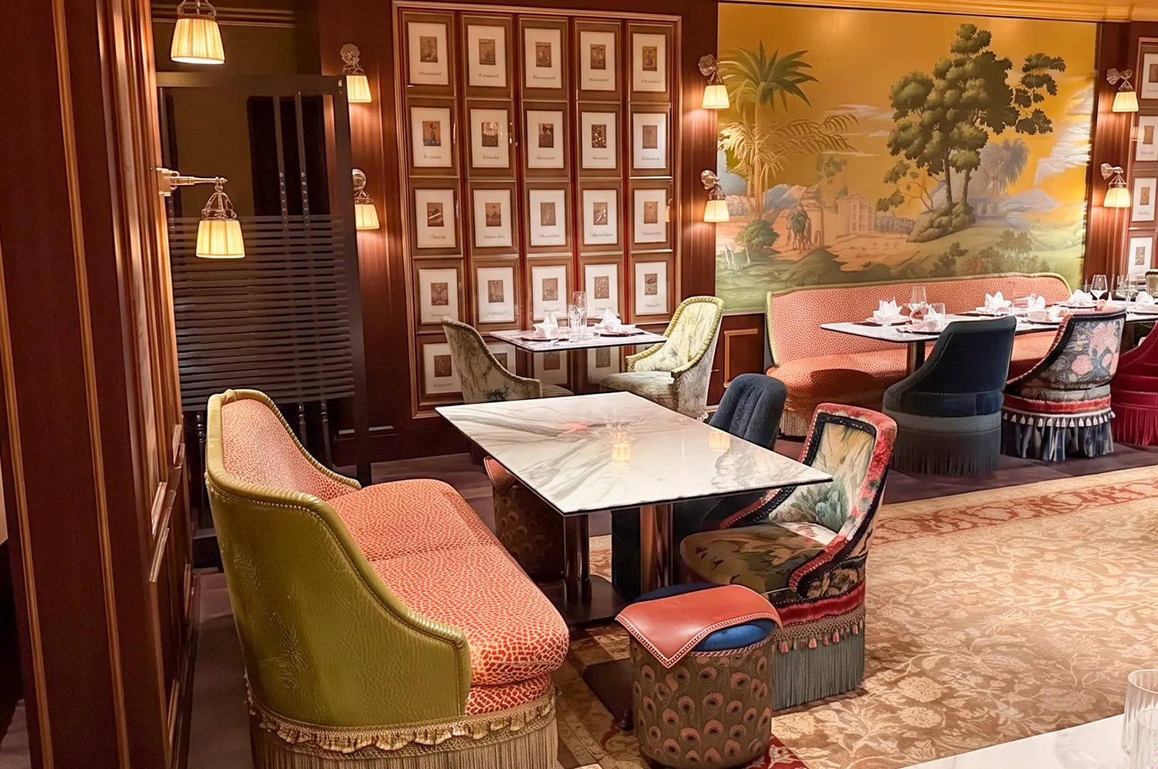 Interior of Cultivate Café featuring elegant tables, eclectic vintage seating, and a large tropical mural wall.