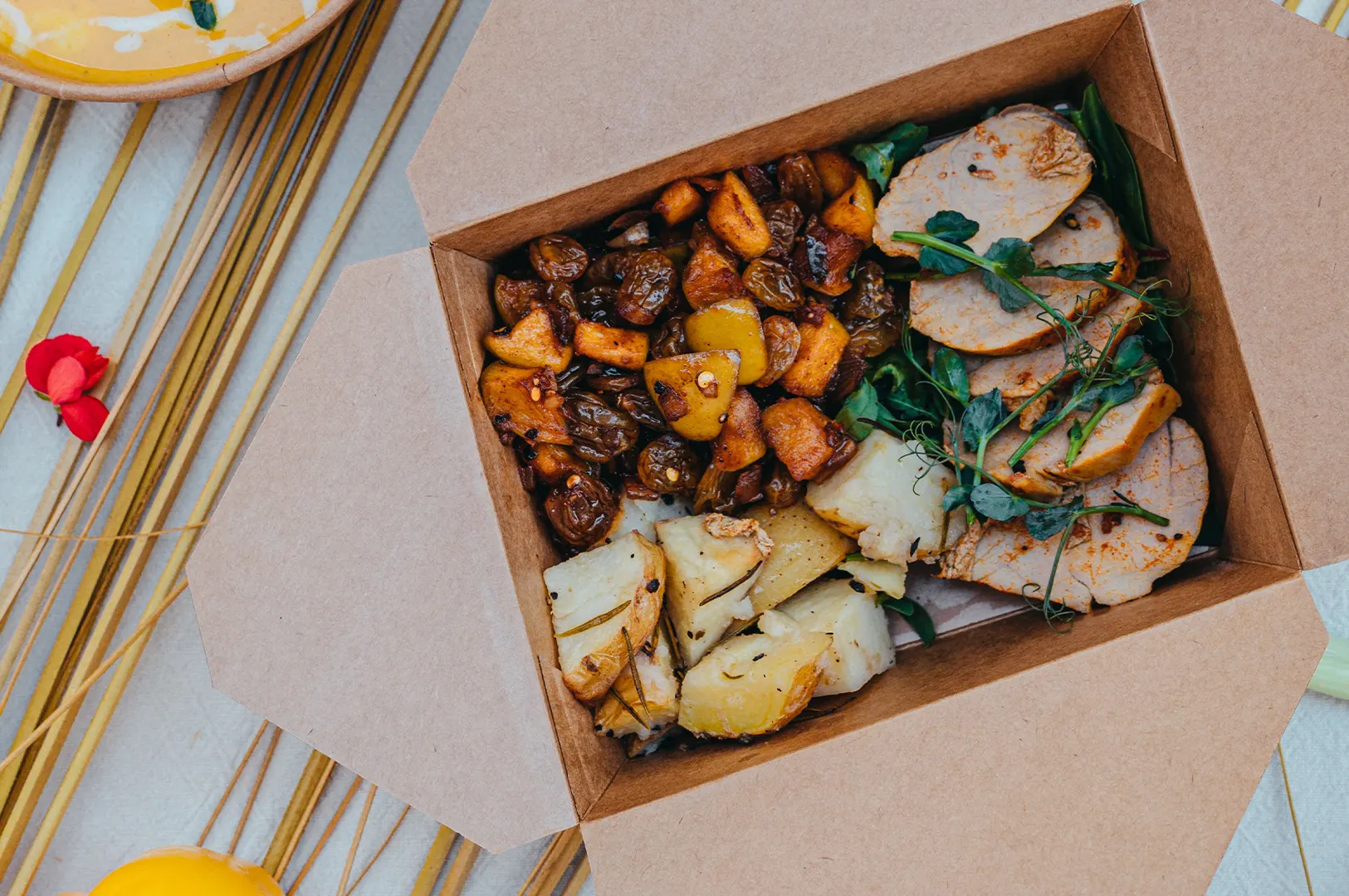 Overhead view of a healthy high-protein meal prep box with lean meat, potatoes, and roasted vegetables.