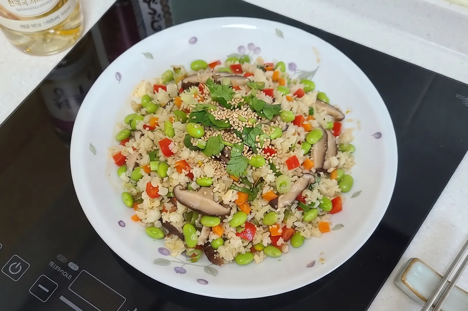 Close-up of Prepped Singapore Smokey Cauliflower Fried Rice plated on a stove, highlighting colorful vegetables, edamame, and shiitake mushrooms.