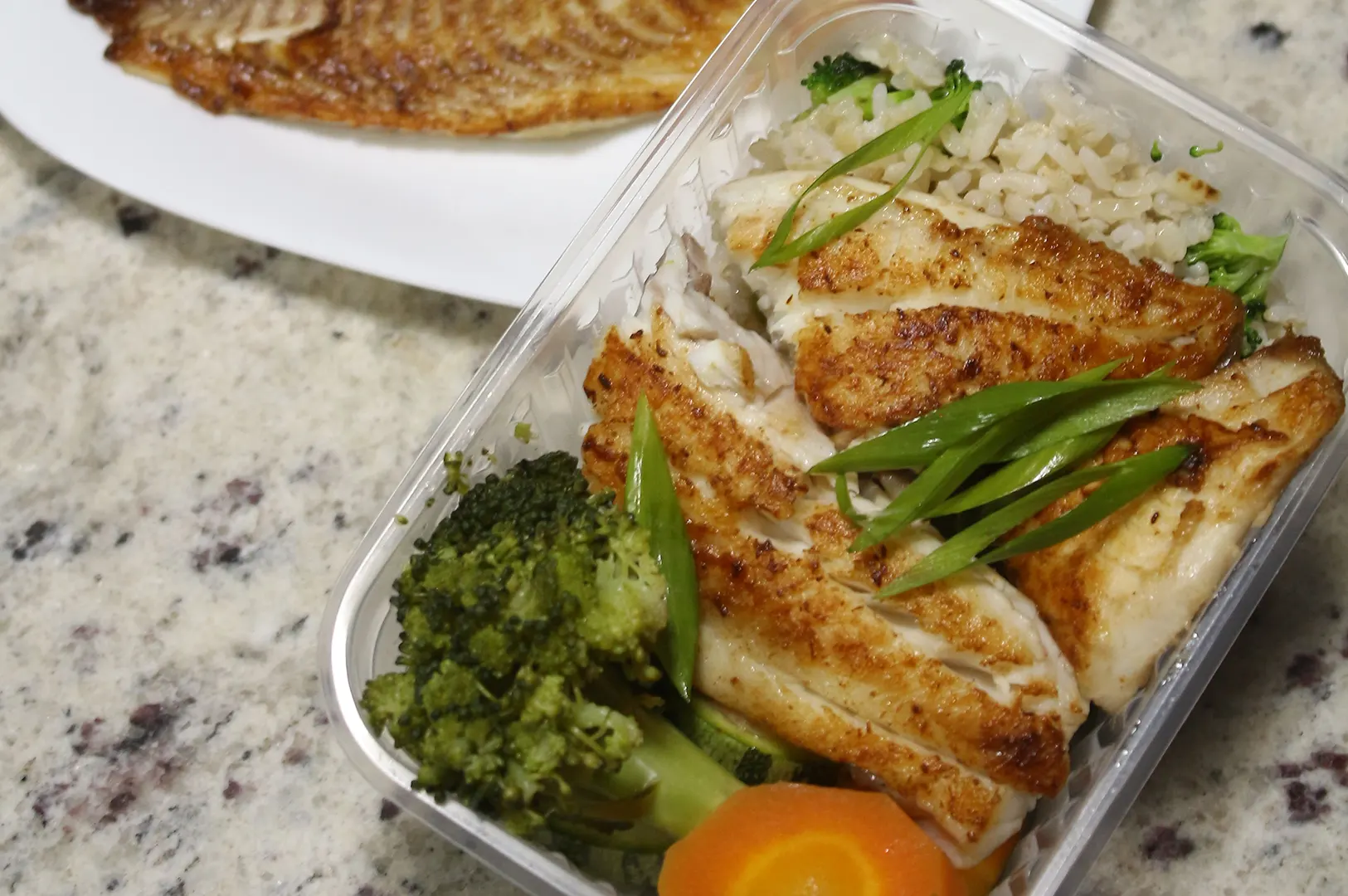 YoloFoods SG weight loss meal plan container with grilled fish, brown rice, broccoli, and vegetables for fitness goals.