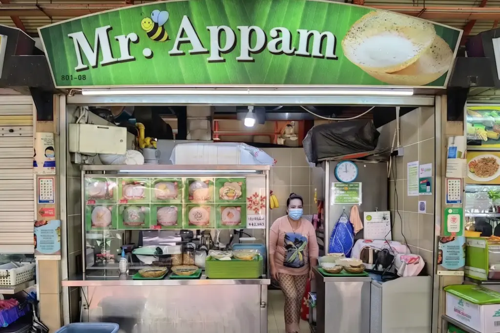 Mr. Appam food stall storefront in a hawker center with a vendor standing inside.