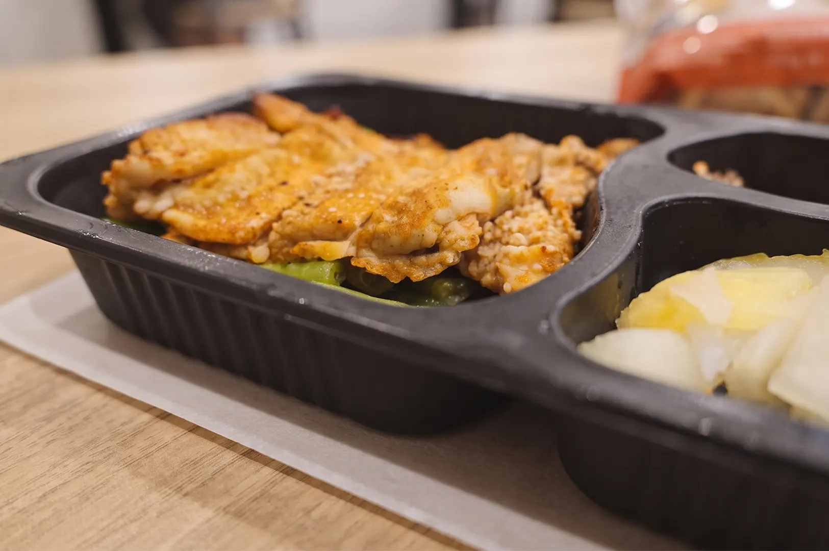 Low-carb meal prep container with keto-friendly chicken dish and side sides from a healthy food delivery service.