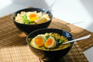 Upgraded instant noodles in a black bowl topped with a soft-boiled egg and green onions for a quick girl dinner.