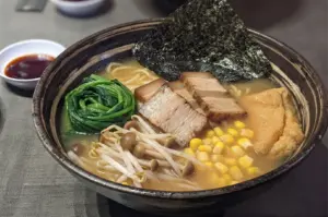 Vegan ramen bowl with noodles, greens, corn, and mock meat at Herbivore Fortune Centre.
