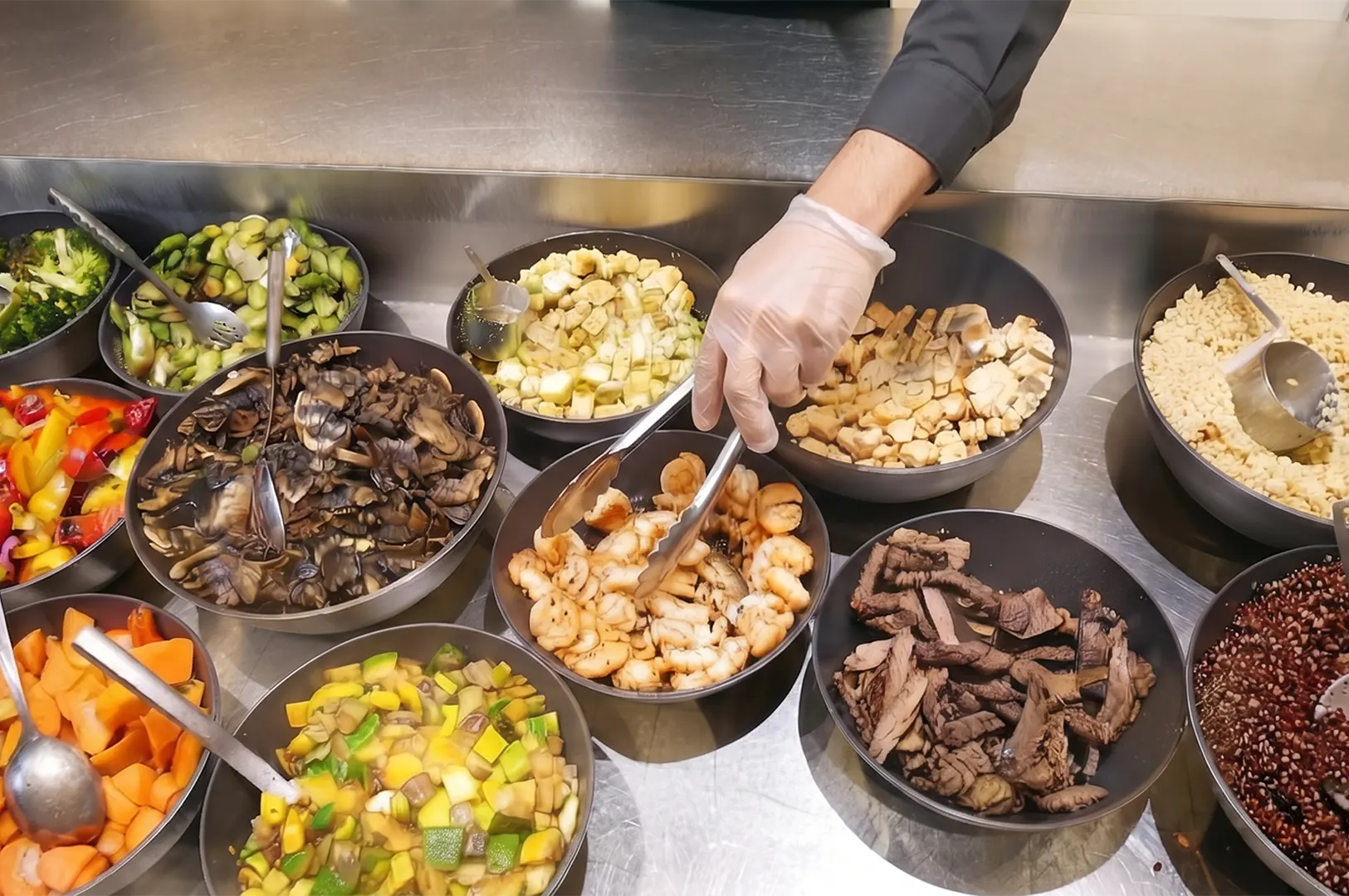 The Daily Cut build-your-own healthy bowl station with bases, proteins, and vegetables.