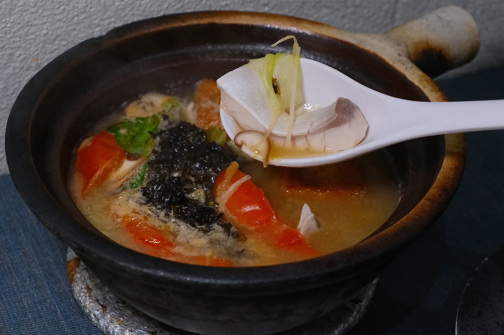 Hup Lok fish soup in clay pot with a spoonful of fresh fish cut.