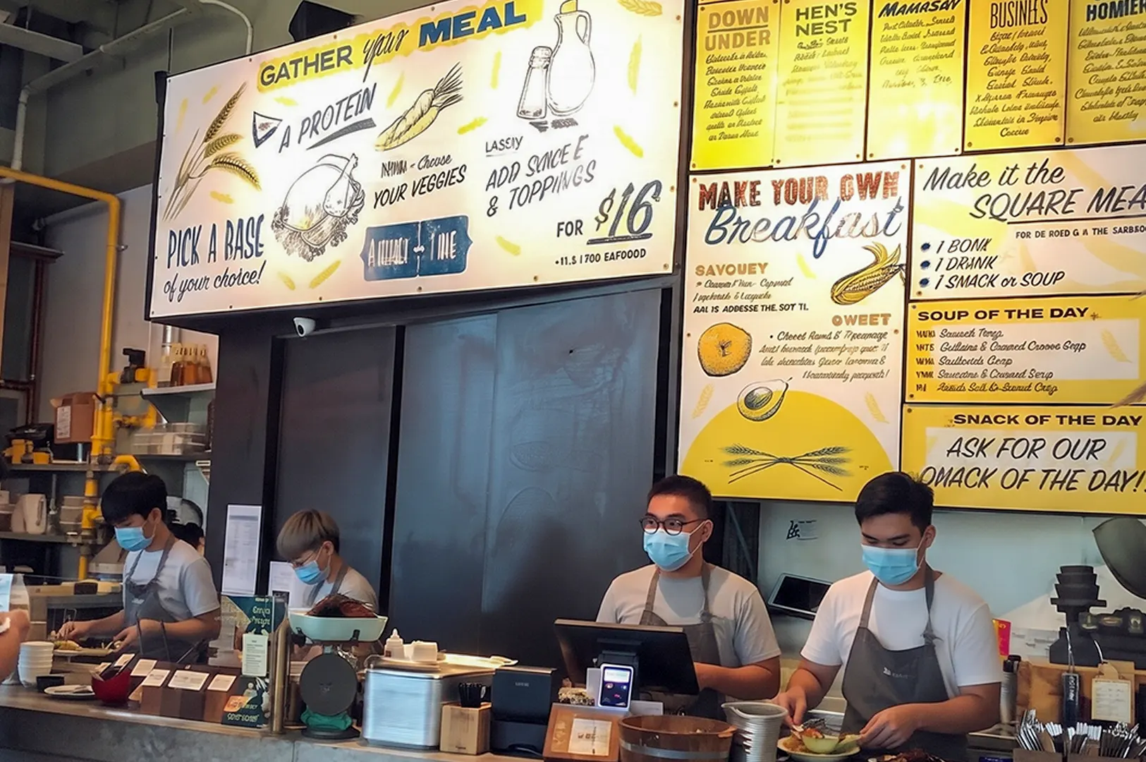Grain Traders menu board and pricing display showcasing meal options with staff serving customers.
