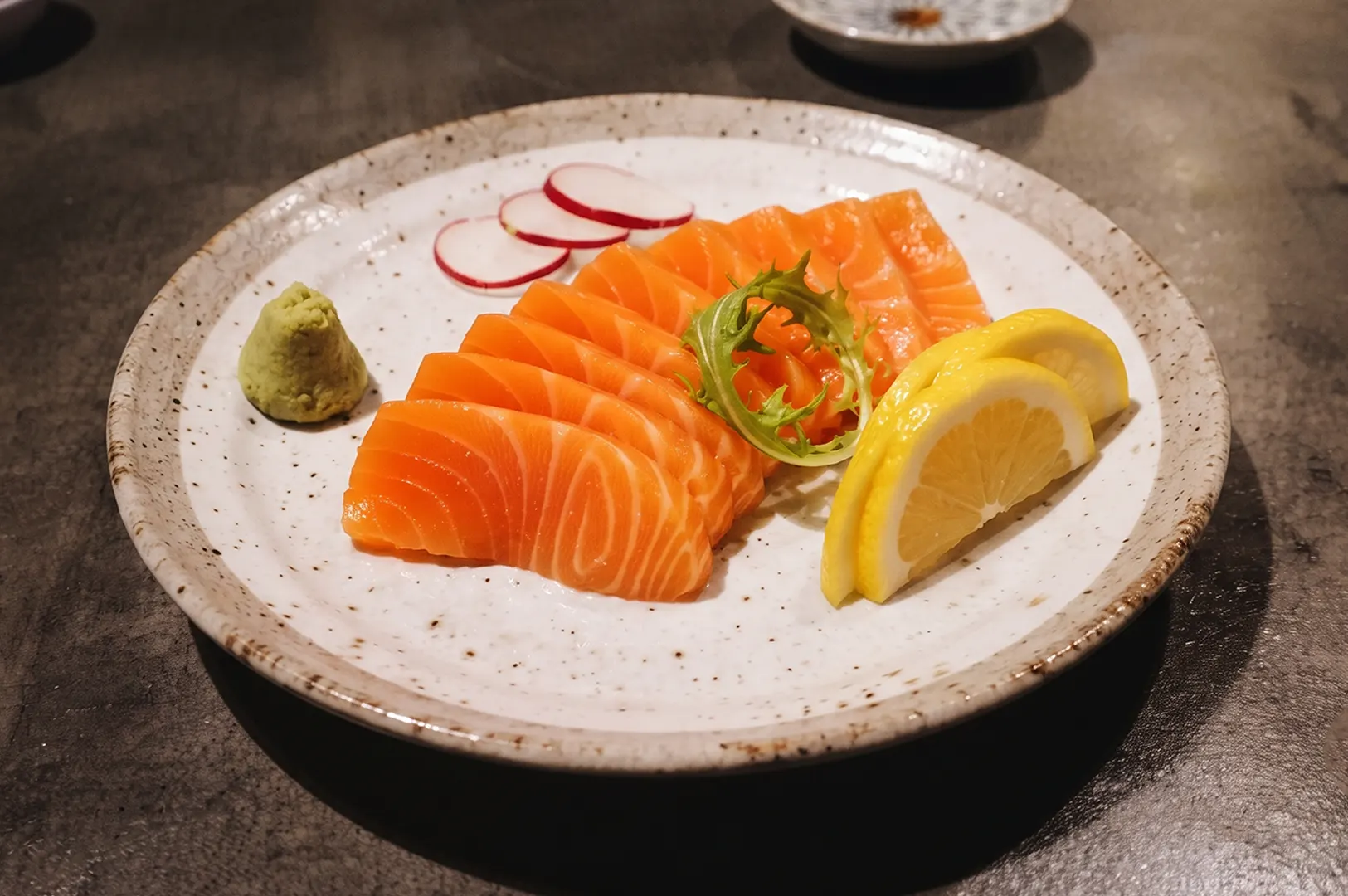 Platter of salmon sashimi served with lemon and wasabi.