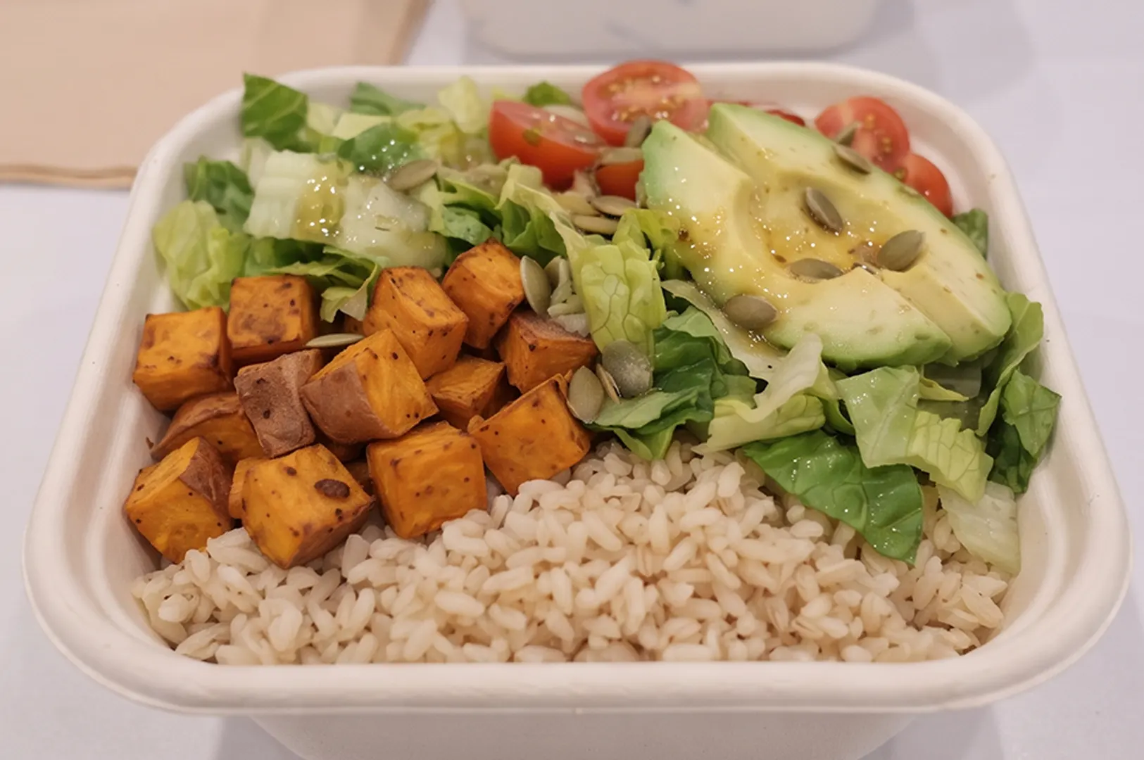 Healthy grain bowl with brown rice, baked sweet potatoes, and romaine lettuce.