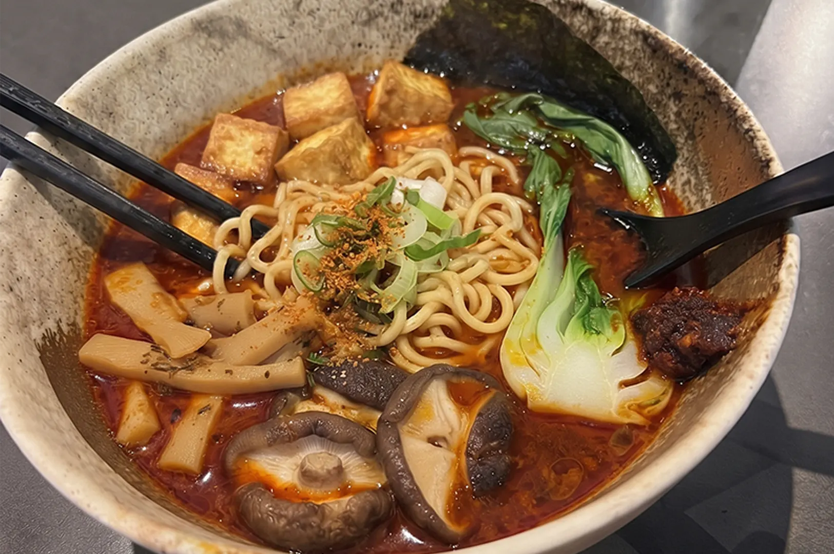 Bowl of spicy vegetarian ramen with tofu and mushrooms.